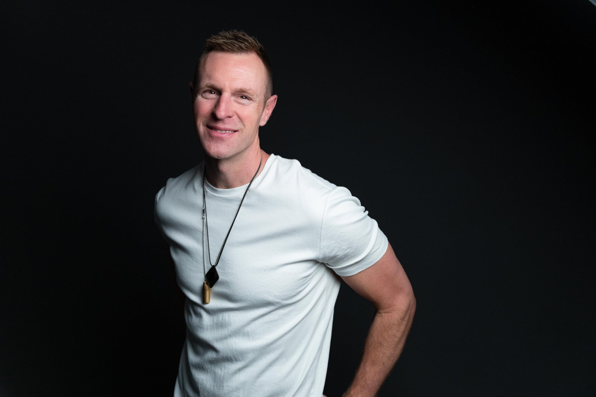 Headshot of Darren Langille in a white t-shirt against a black background